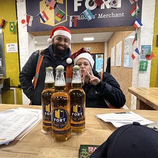 Two FORT colleagues with FORT beers wearing Christmas hats. 