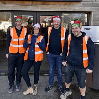 Image of 4 colleagues from the FORT sales team wearing Christmas hats in front of the FORT shop entrance. 