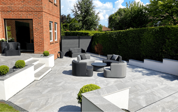 Picture of sunlit garden with outdoor furniture featuring porcelain paving. 