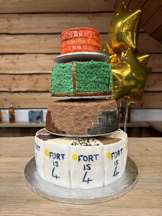 FORT Builders' Merchant celebrates their 4th birthday with this fantastic cake as a showpiece. 3 tiers displaying designs of aggregate bays, roofing tiles & artificial grass.