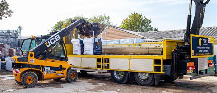 FORT Builders' Merchant truck with raised arm and forklift loading on two jumbo tonne bags for delivery.