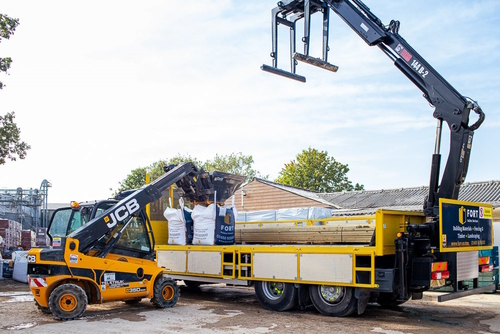 FORT Builders' Merchant truck with raised arm and forklift loading on two jumbo tonne bags for delivery.