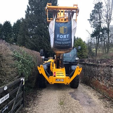 Grab truck lifting tonne bag of aggregates, down a very narrow lane.